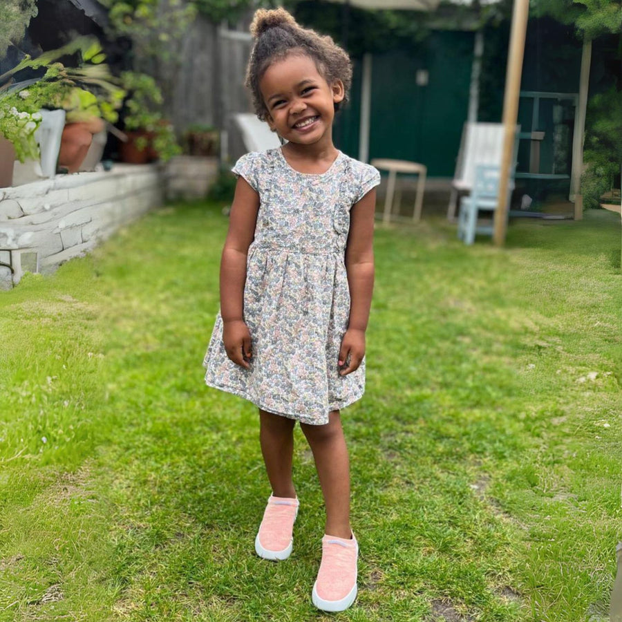 girl wearing pink slip on trainers in garden