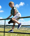 boy climbing gate wearing blue sustainable trainers